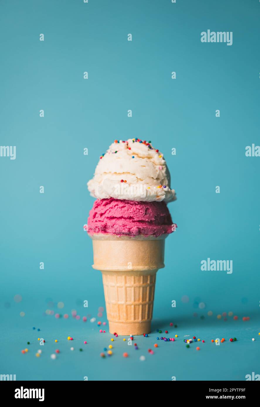 Ice cream cone with two scoops and sprinkles on blue background Stock