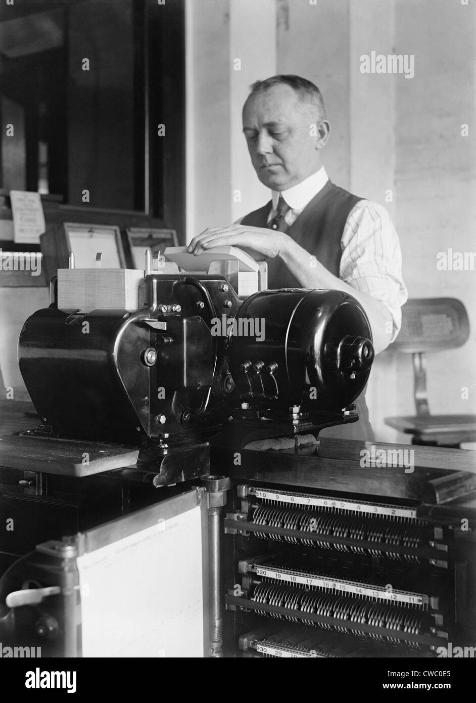 Man loading punch cards into a tabulating machine used in the 1920