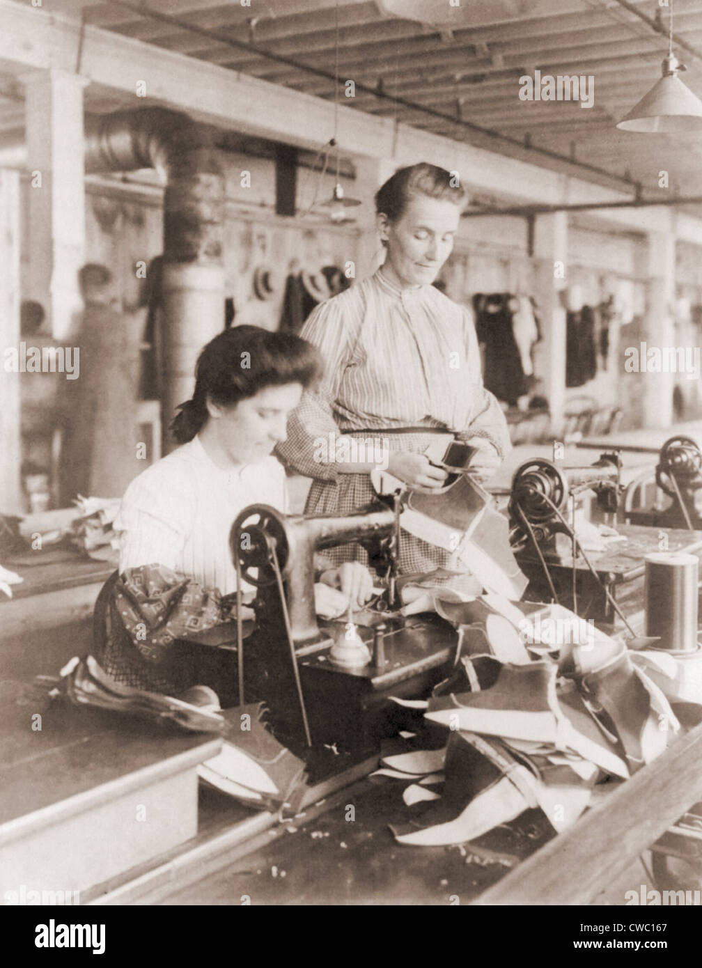 Woman operating a belt driven sewing machine at a shoe factory in Lynn