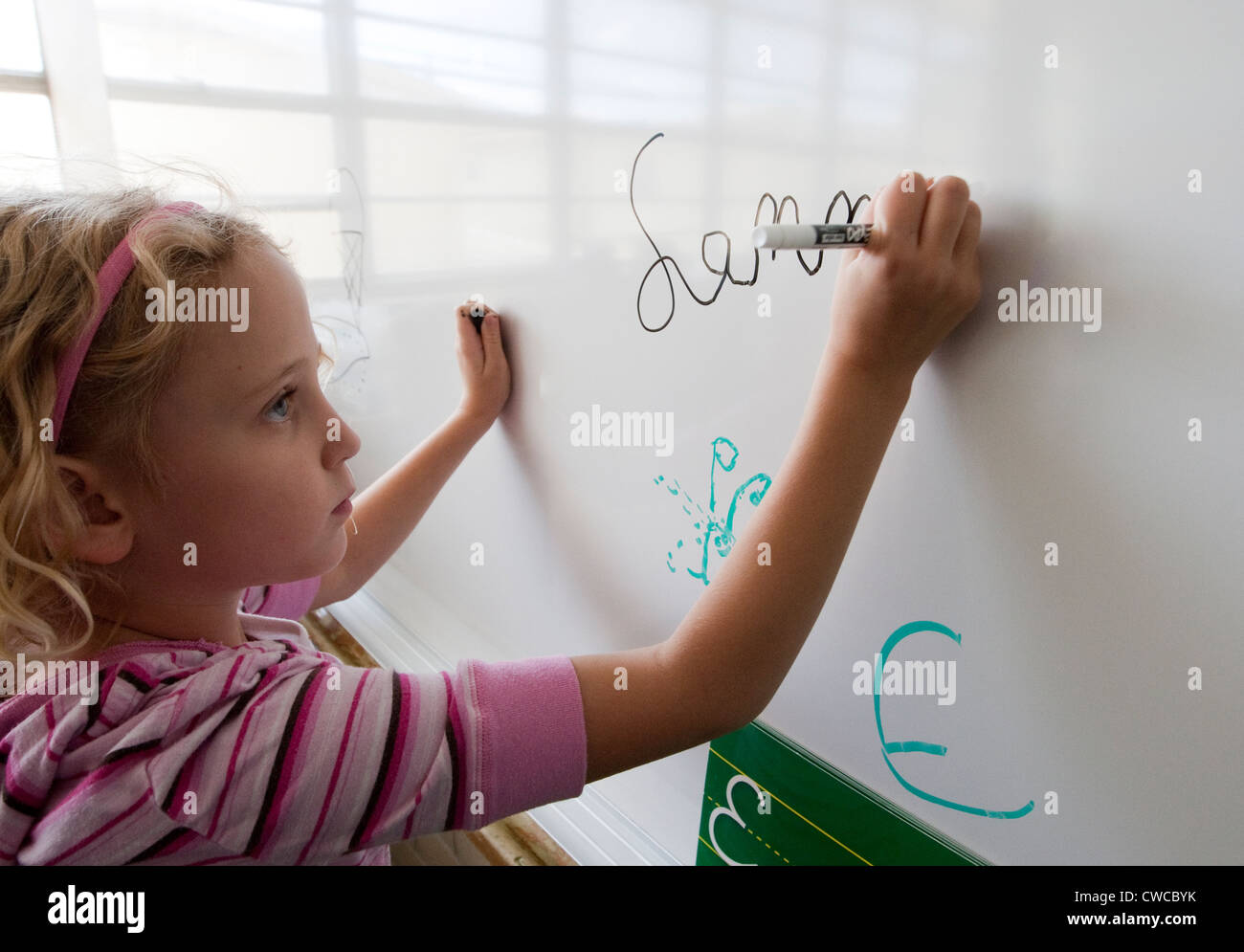 7 year old girl practices writing her name in cursive on white board