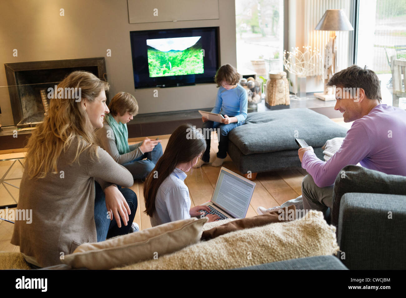 Family using electronic gadgets in a living room Stock Photo Alamy