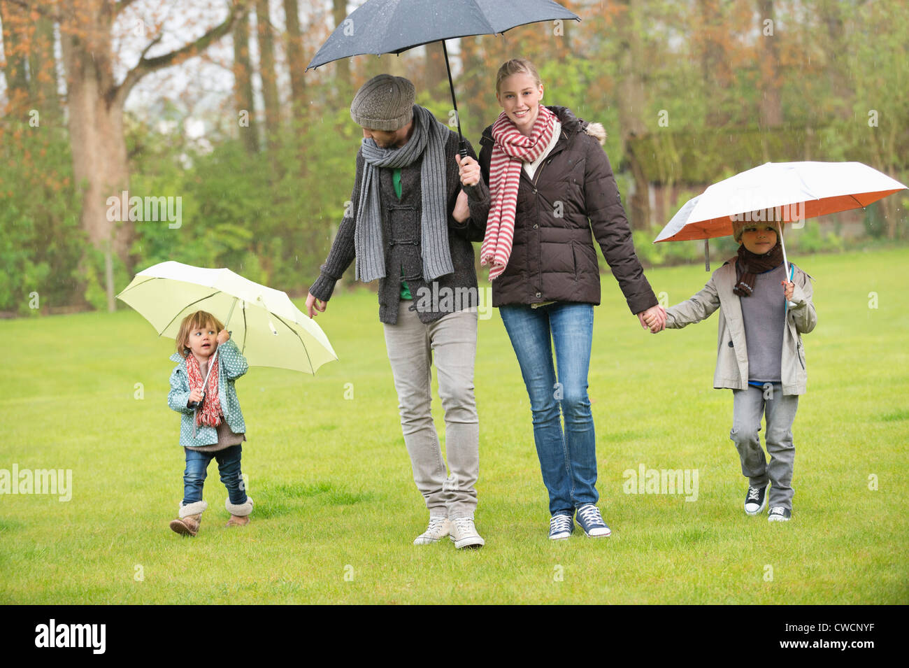 Family walking with umbrellas in a park Stock Photo Alamy
