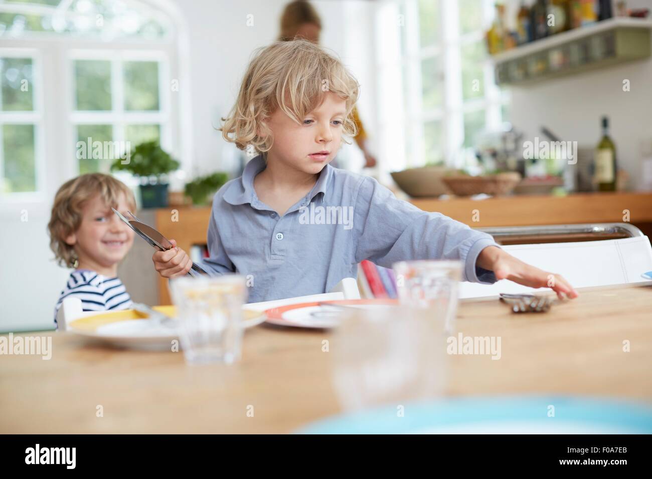 Boy setting table in kitchen Stock Photo Alamy