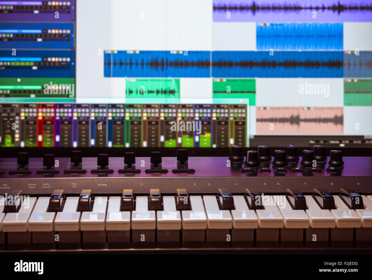 Midi keyboard and controller with faders and buttons. Waveforms in a