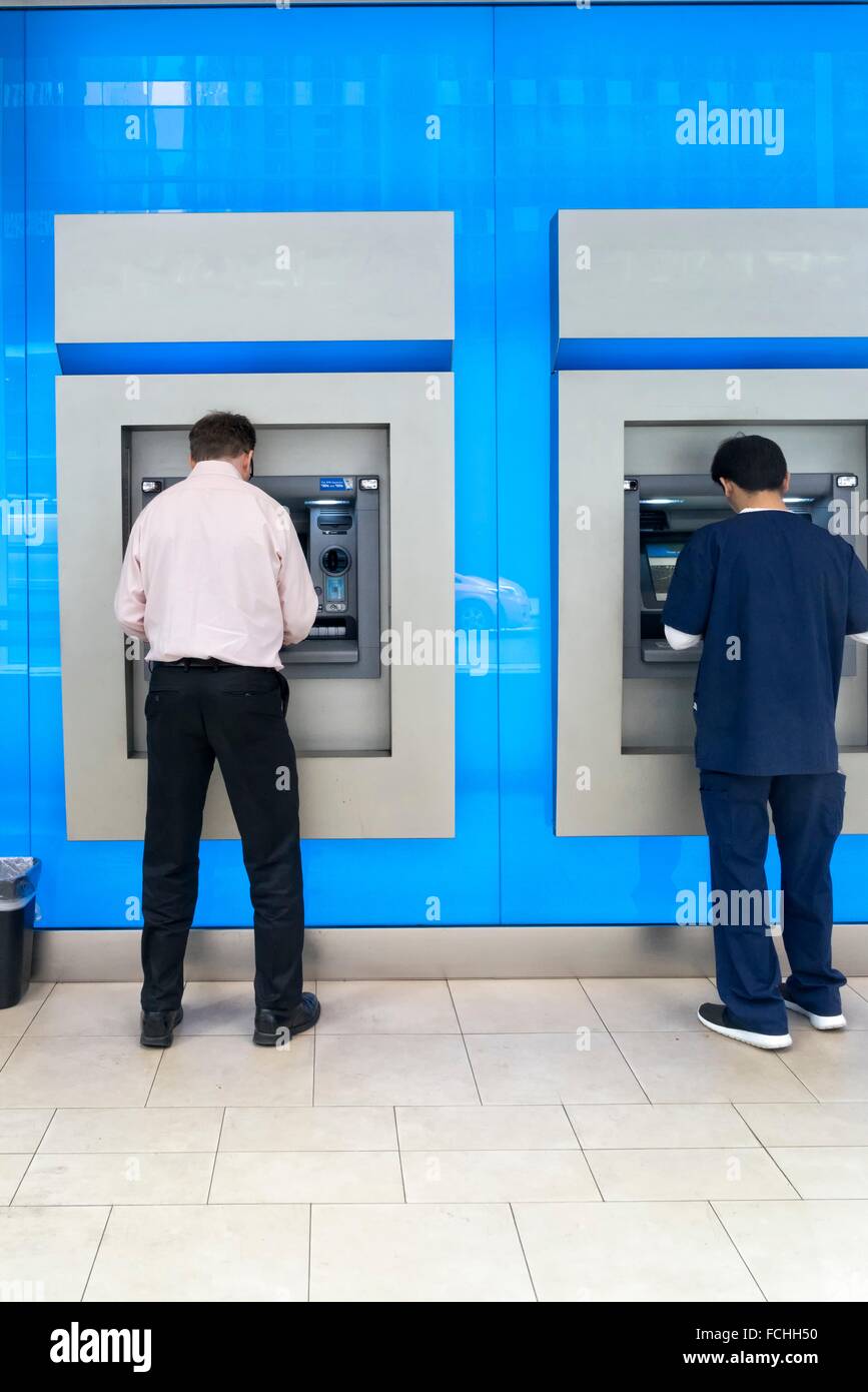 Two Men in a Bank Lobby, Using the ATM Machines Stock