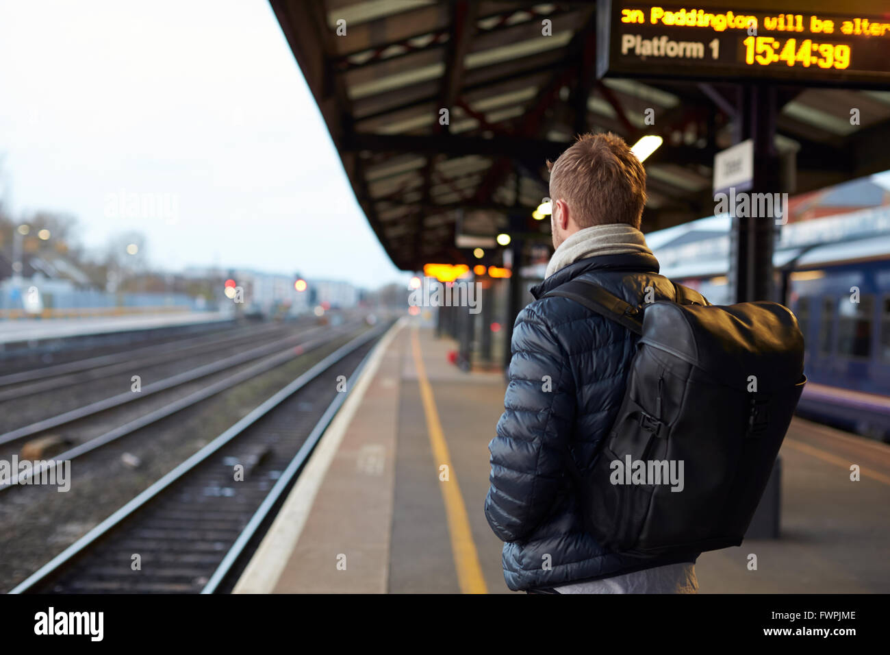 Man Standing On Railway Platform Waiting For Train To Arrive Stock