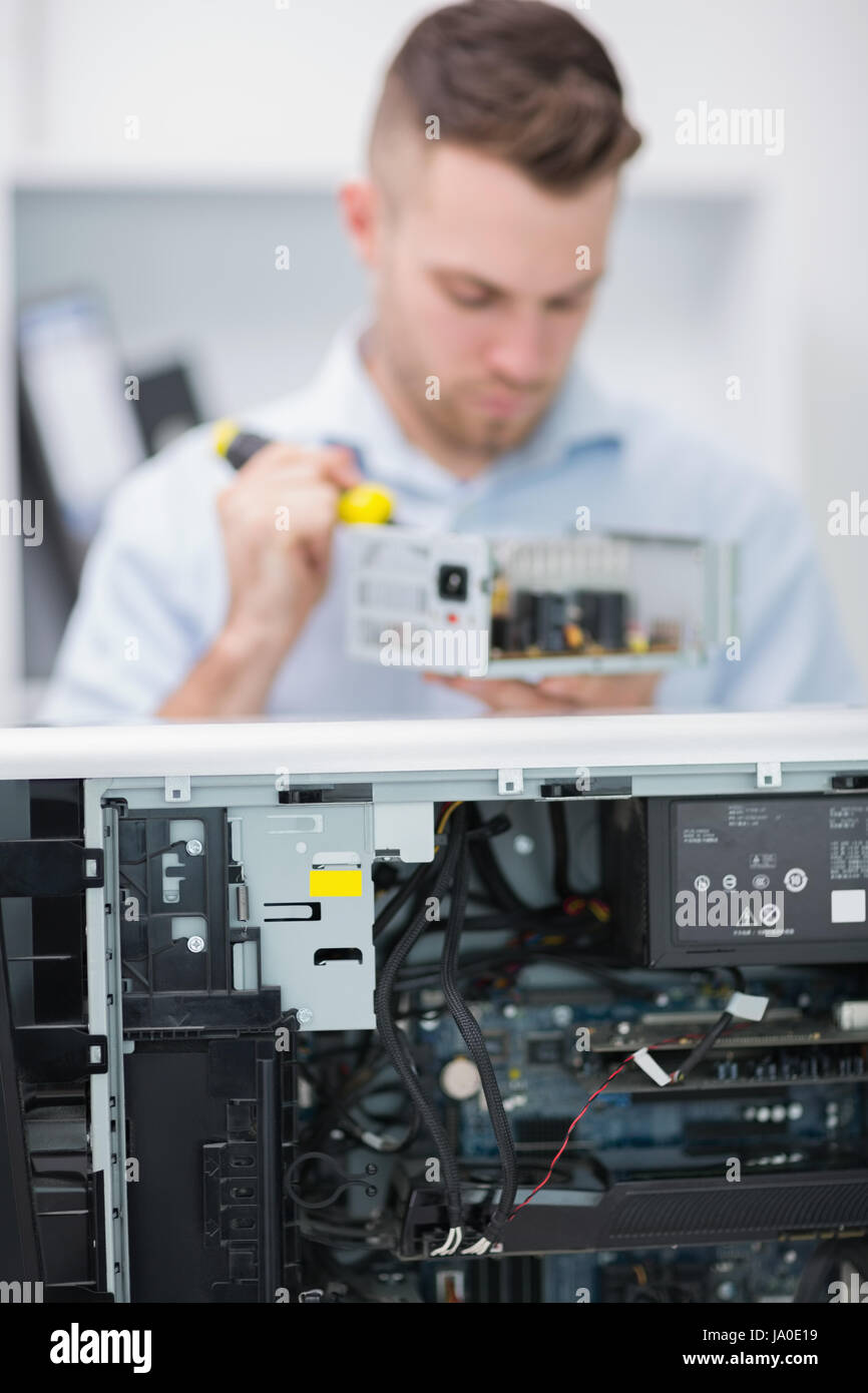 Young computer engineer working on cpu part in front of open cpu at