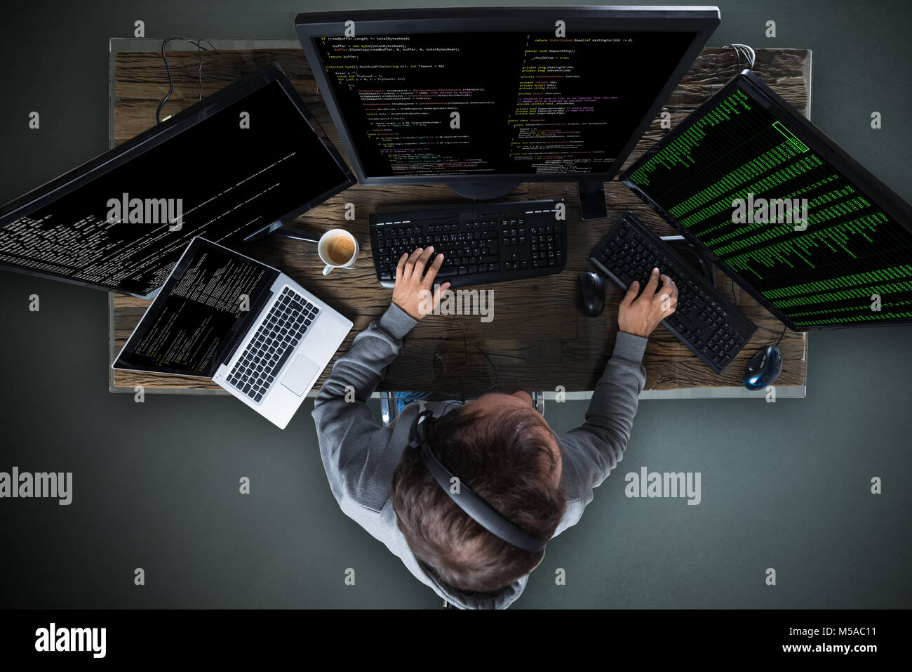 High Angle View Of Hacker Hacking Multiple Computers On Desk Stock