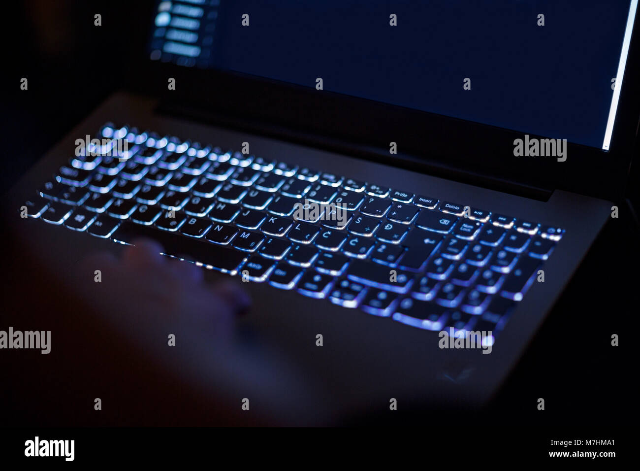 Programmer or computer hacker typing code on laptop keyboard late night