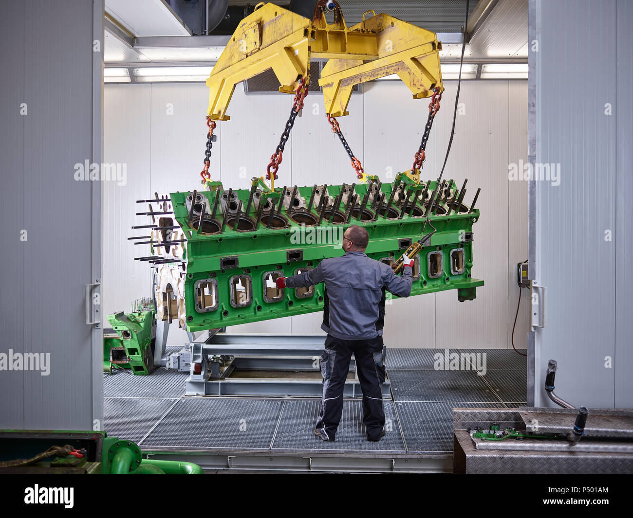 Worker in factory lifting engine block with crane Stock Photo Alamy