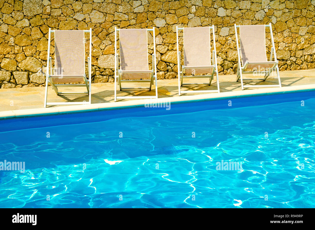 pool with chaiselongues in hotel Stock Photo Alamy
