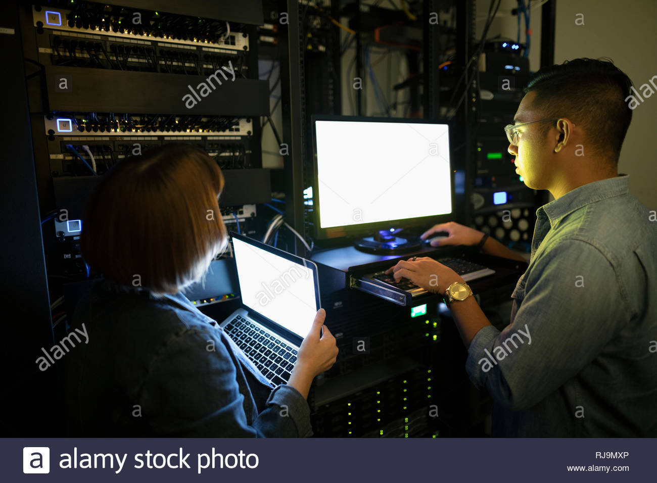 IT technicians using laptops in dark server room Stock Photo Alamy