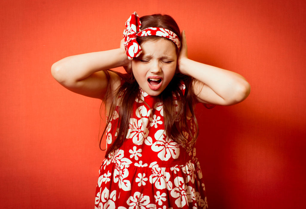 Little girl covering her ears, looking troubled