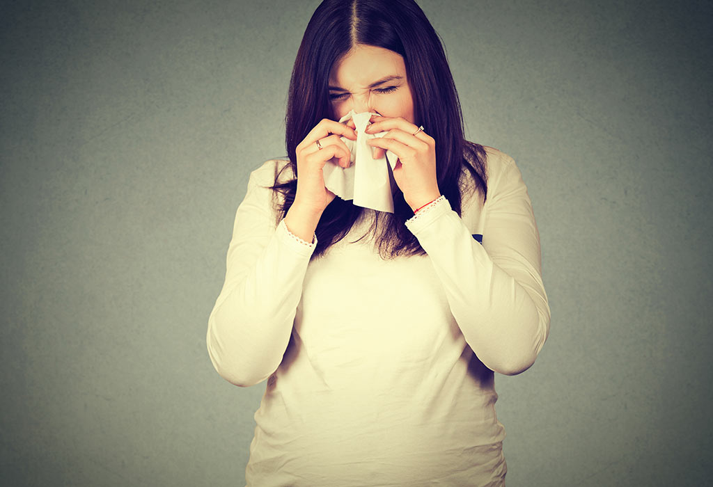 A pregnant woman sneezing