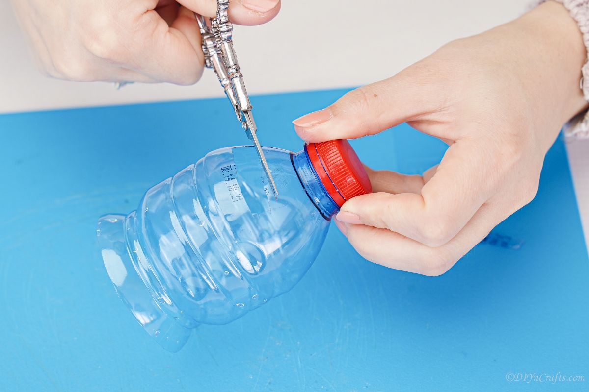scissors cutting plastic bottle with red lid