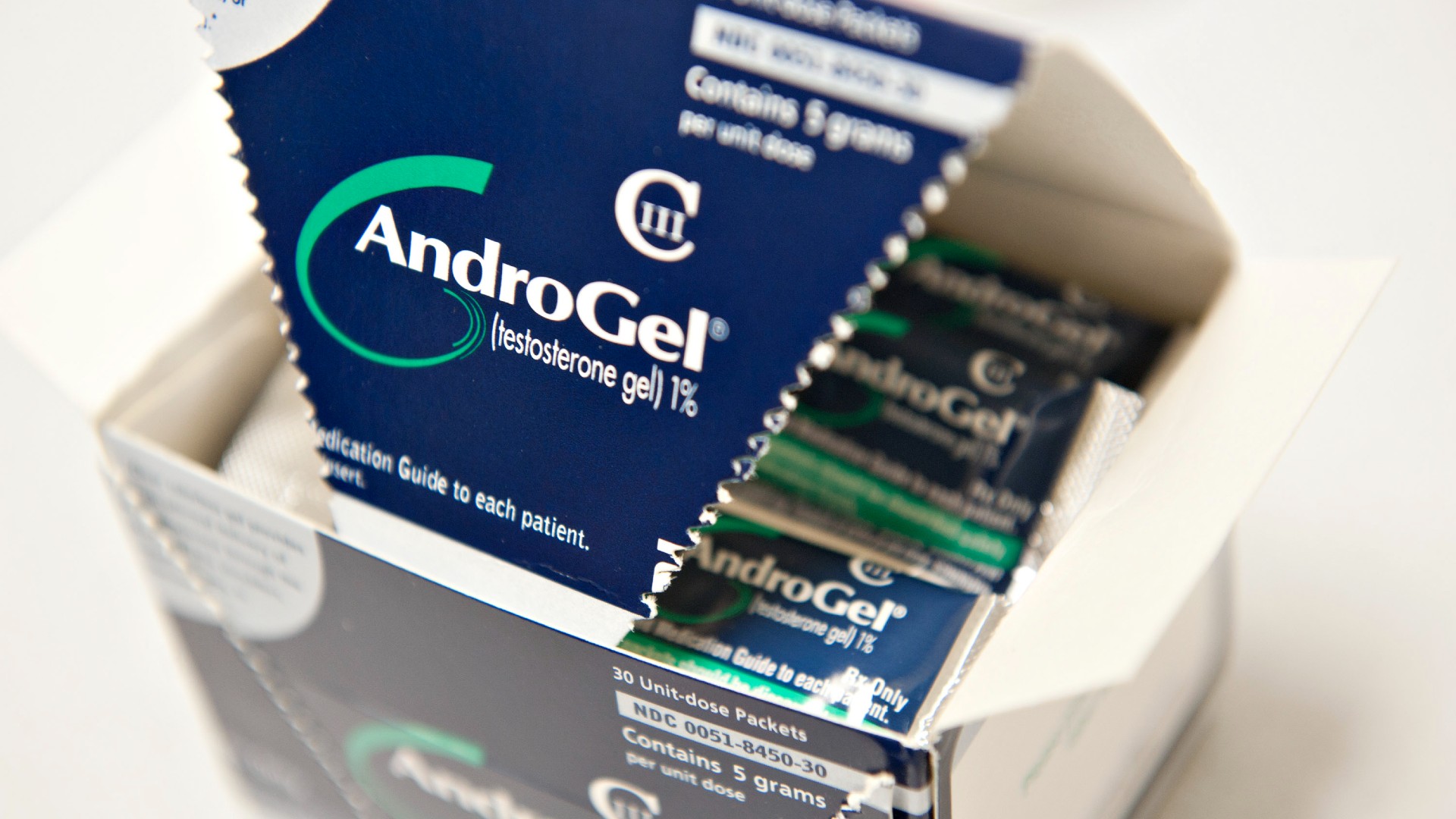 Close-up picture of a blue and white box of AndroGel, aka testosterone gel, containing individual packets of the gel
