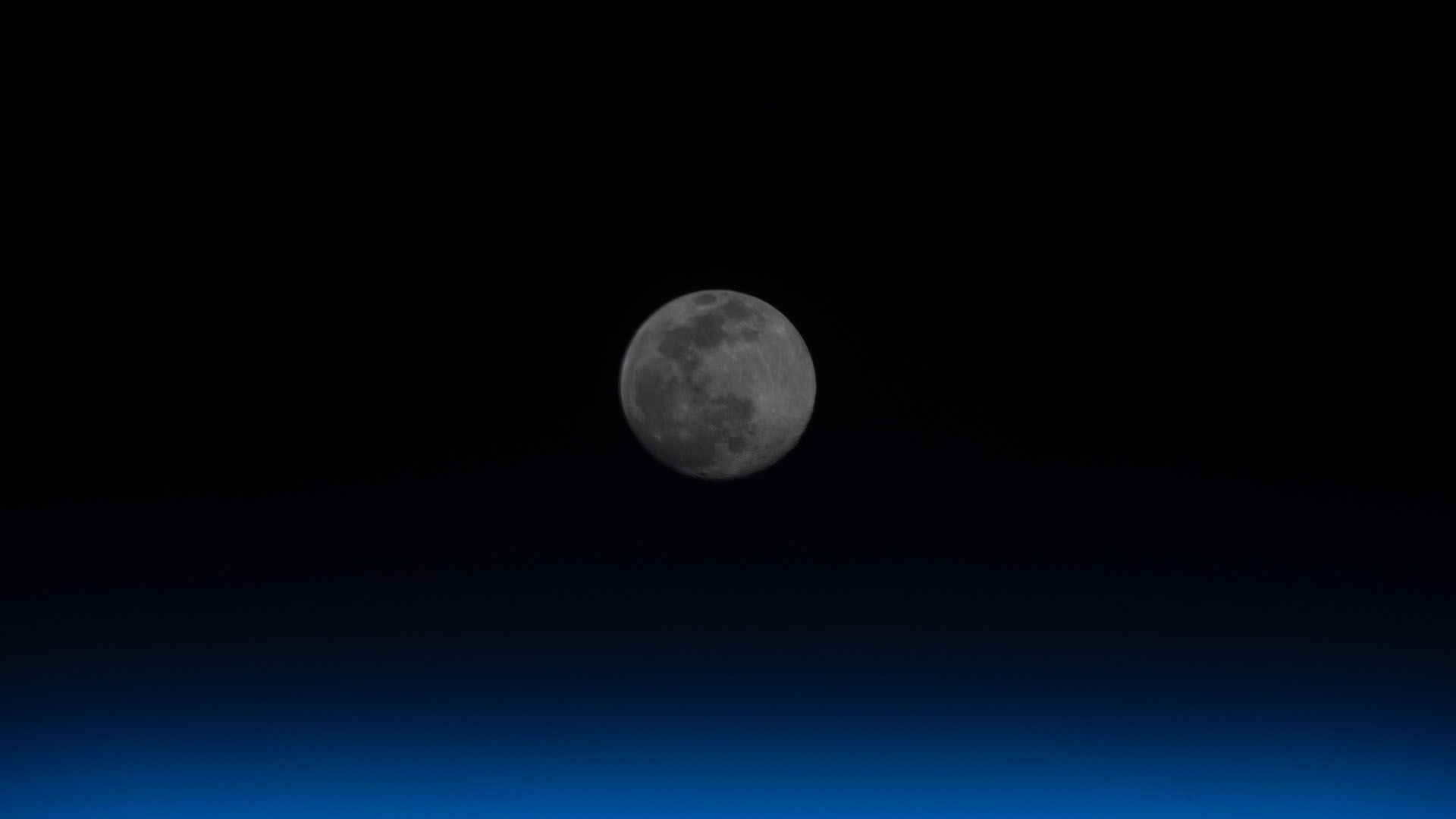 A full moon is pictured above the Earth&rsquo;s horizon.
