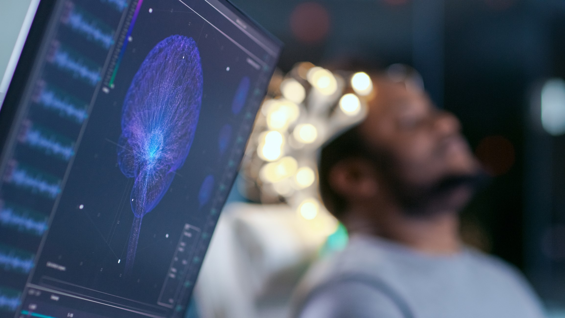A patient sits in the background while a computer scans his brain.