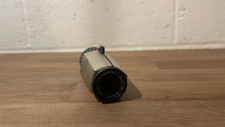 Nikon 5x15 HG tumbada sobre una superficie de madera con el objetivo mirando hacia la cámara