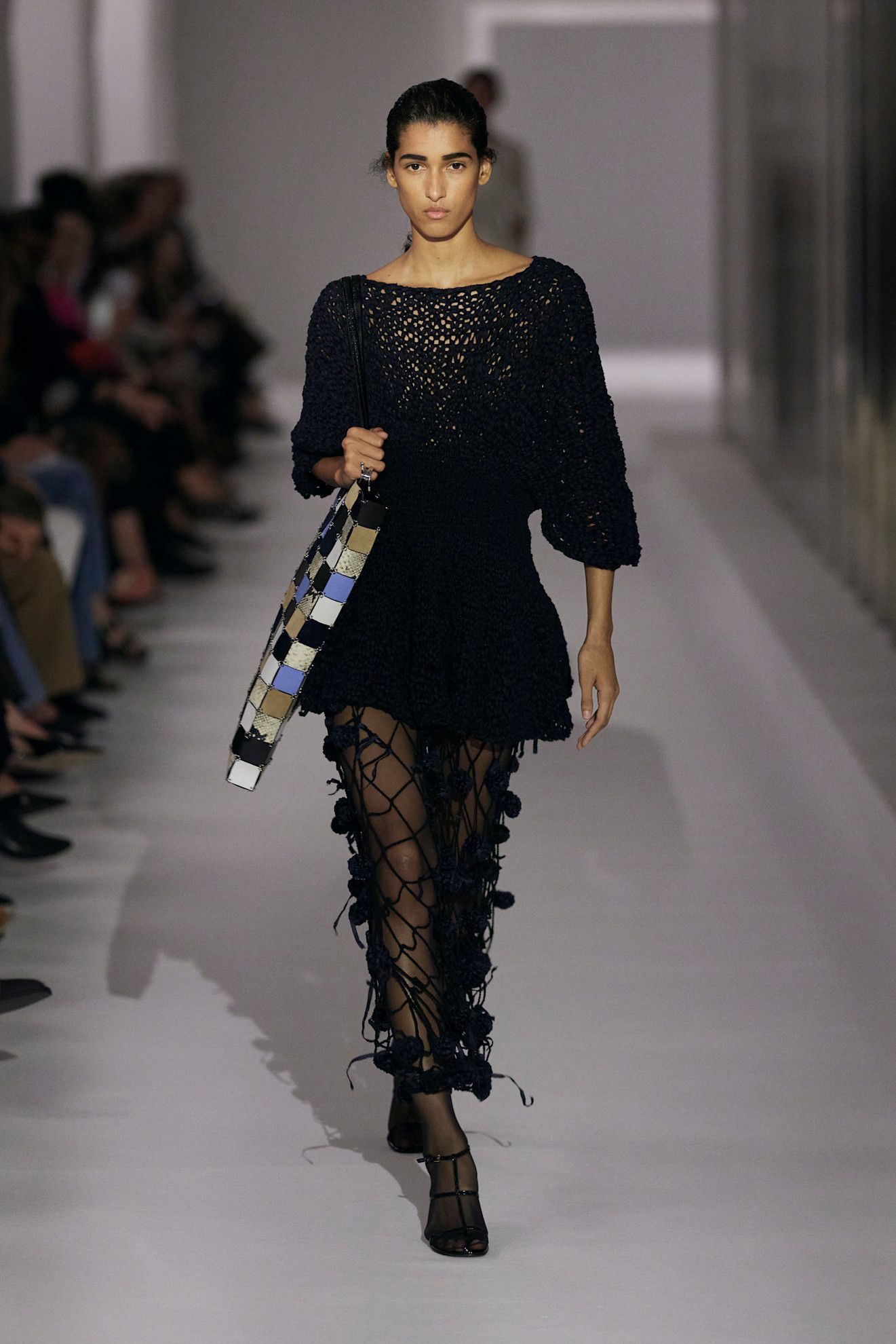 A model at the Khaite show during S/S 25 fashion week wearing a loose-knit cotton sweater with a crochet skirt and tights.