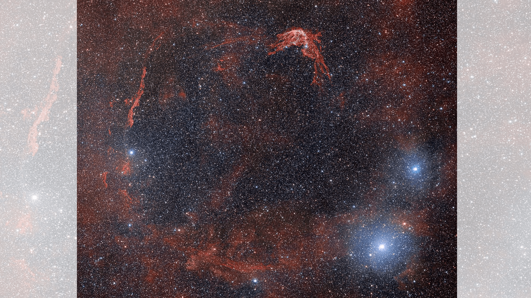 Ghostly red scraps circle around a field of stars in this telescope image of a supernova remnant