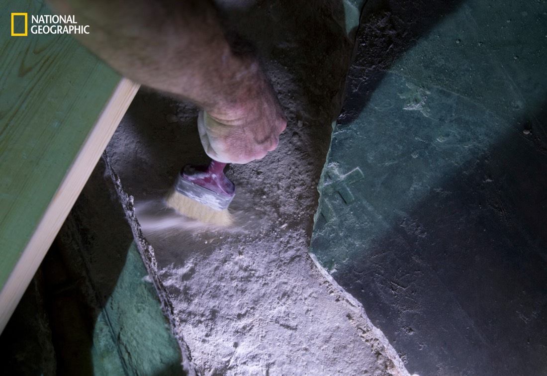 A restorer brushes loose dirt and dust from the original limestone surface of what is said to be the tomb of Jesus Christ.