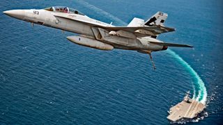 Un avión de combate despega de la superficie de un portaaviones en el mar.