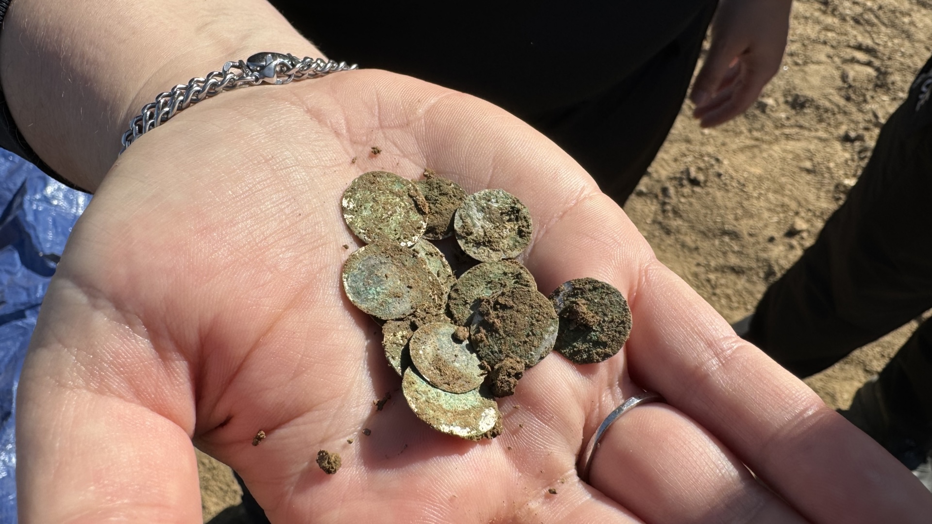 silver coins in a man�s hand covered with dirt
