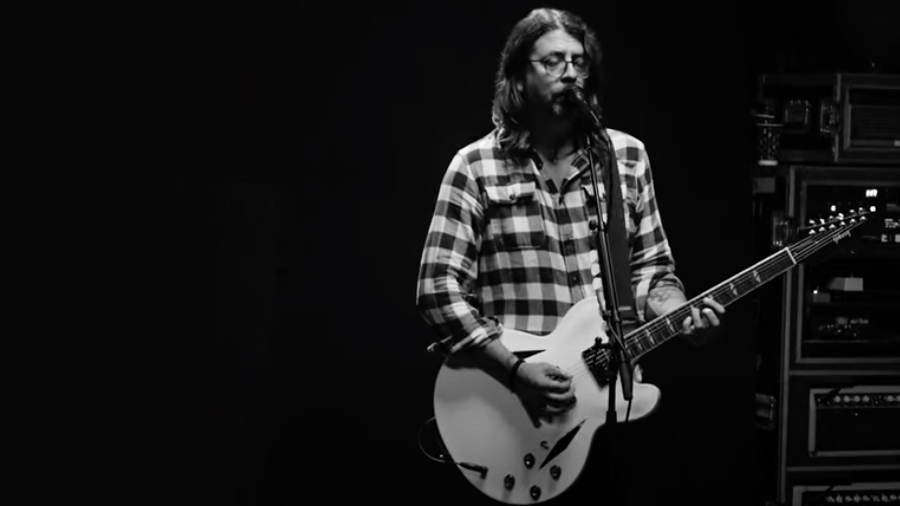 Dave Grohl plays a white Gibson DG335 custom signature guitar as Foo