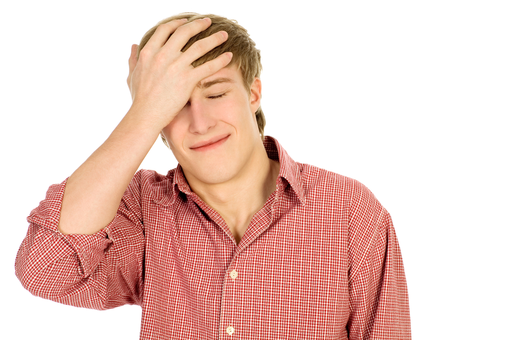 A man stands with his hand covering his forehead