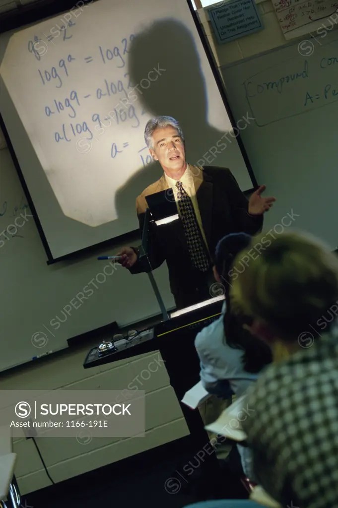 Male teacher explaining with the help of an overhead projector SuperStock
