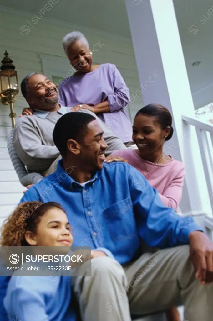 Grandparents sitting on the front porch with their son and