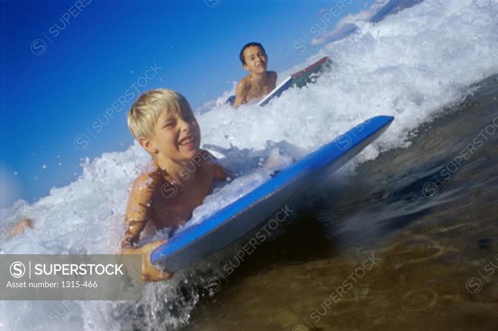 Low angle view of children surfing on boogie boards, Maui, Hawaii, USA