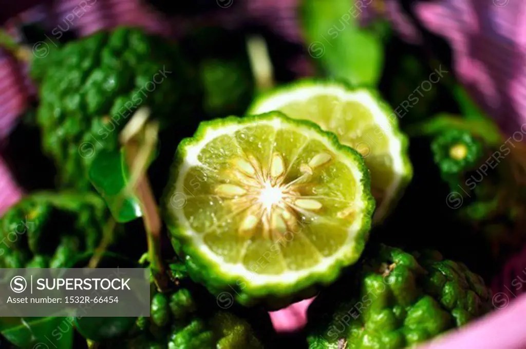 Thai limes with wrinkled skin, whole and halved SuperStock