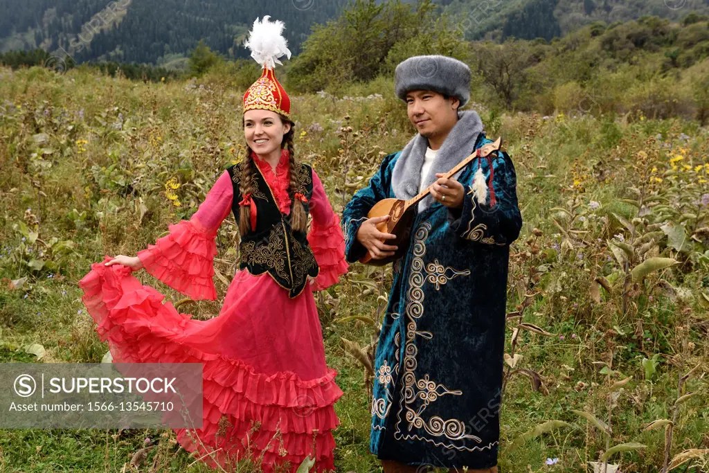 Young man and woman in traditional Kazakh clothing in a field at Huns
