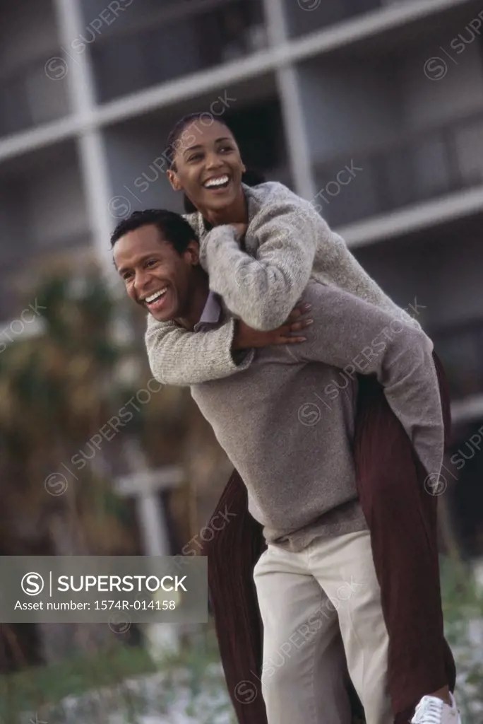 Mature woman riding piggyback on a mature man - SuperStock