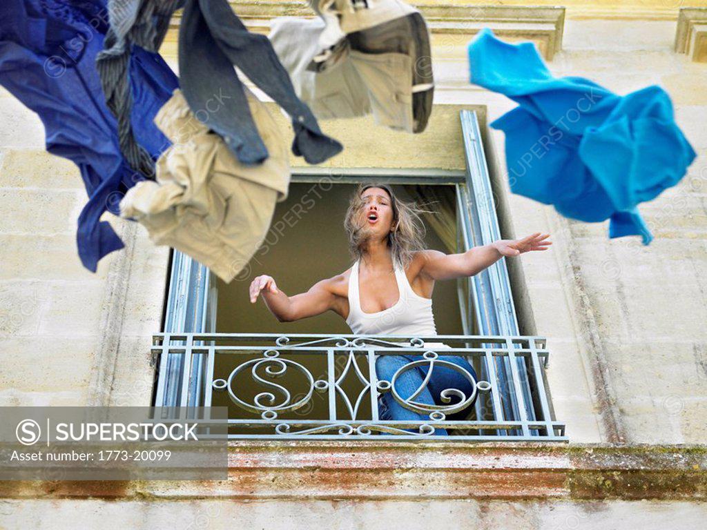 Woman throwing clothes by the window SuperStock
