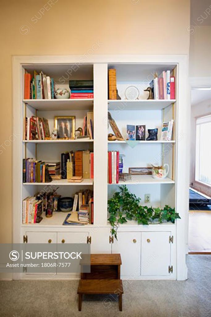 Large cluttered built in bookcase with small stepping stool SuperStock