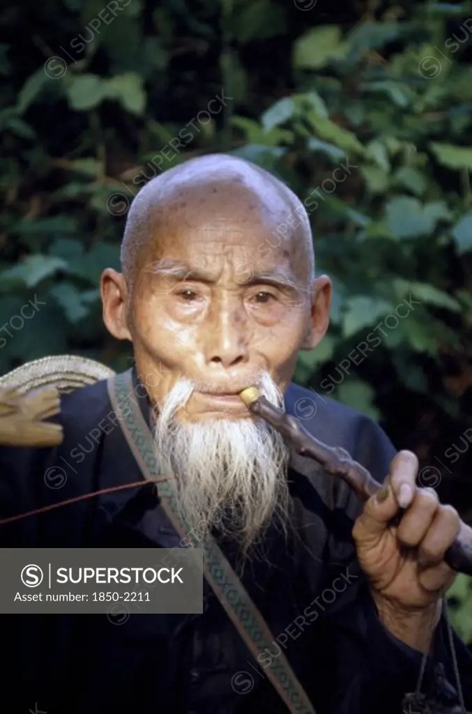 China, South, Portrait Of An Old Man Smoking A Pipe SuperStock