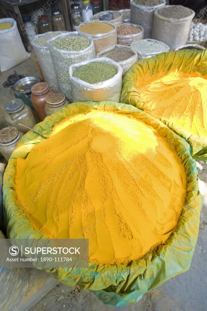 Spice market stall with large bowls of turmeric powder in early morning
