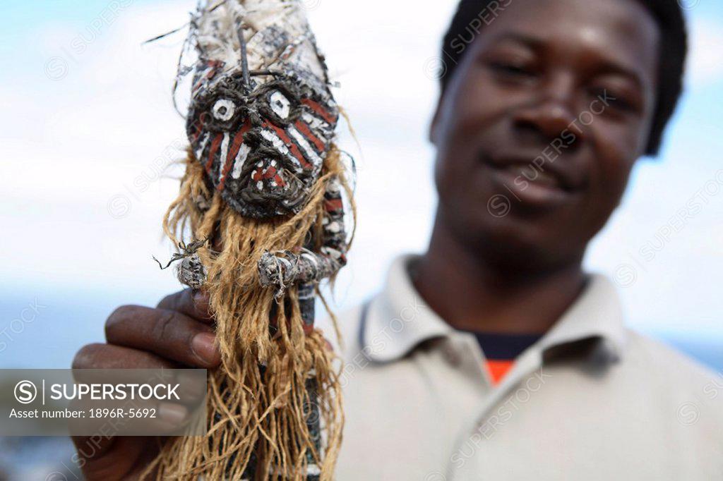 Man Holding up an African Voodoo Doll Cape Town, Western Cape Province, South Africa SuperStock