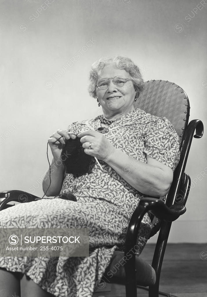 Smiling elderly woman sitting in rocking chair knitting SuperStock