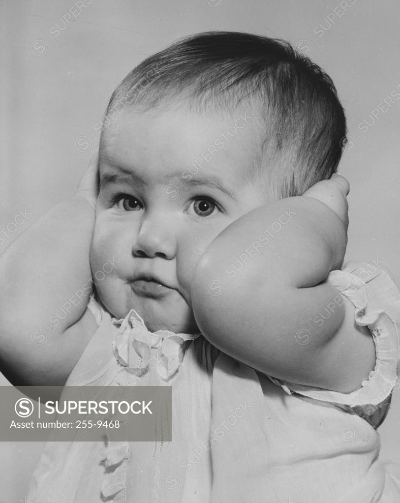 Baby girl covering ears with hands SuperStock