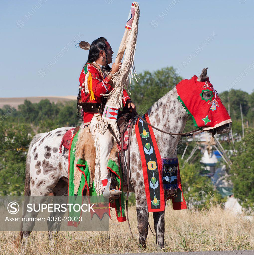 A traditionally dressed Crow Indian man rides an appaloosa horse during the parade, at the