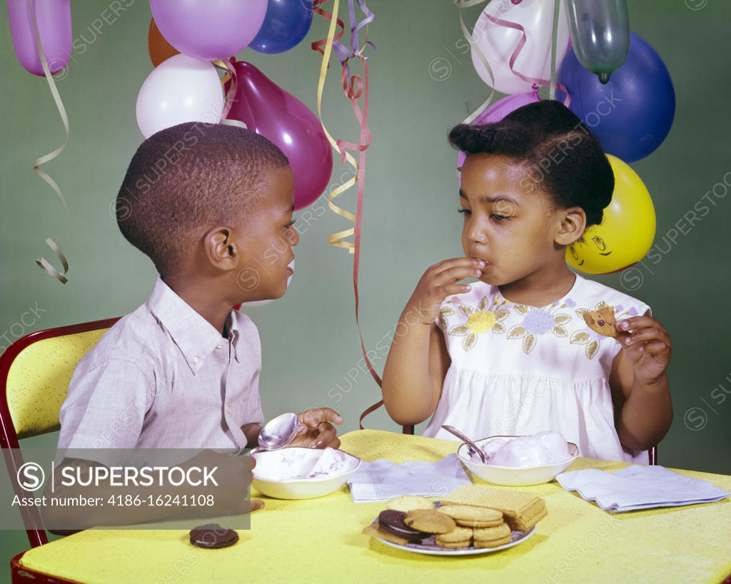 1960s AFRICANAMERICAN BOY AND GIRL SHARING EATING ICE CREAM AND