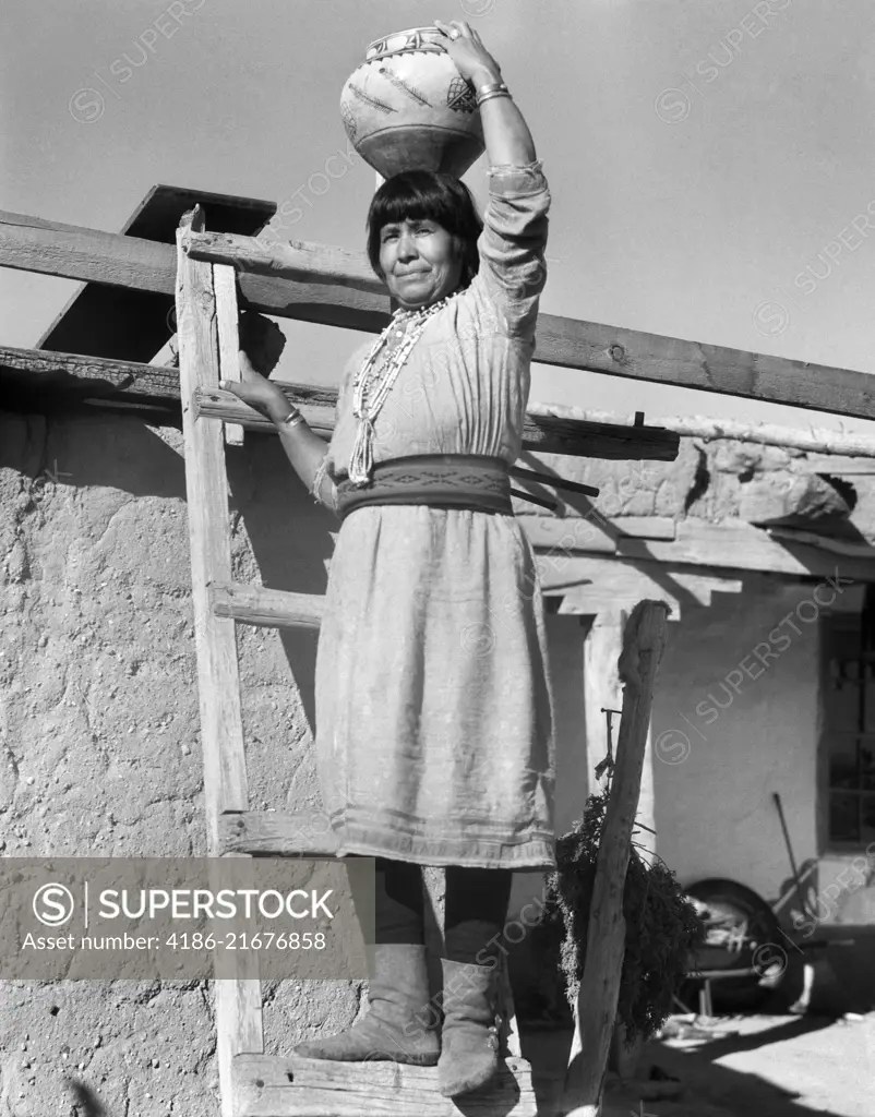 1930s NATIVE AMERICAN INDIAN WOMAN ON LADDER HOLDING OLLA POTTERY JAR ON HER HEAD COCHITI PUEBLO