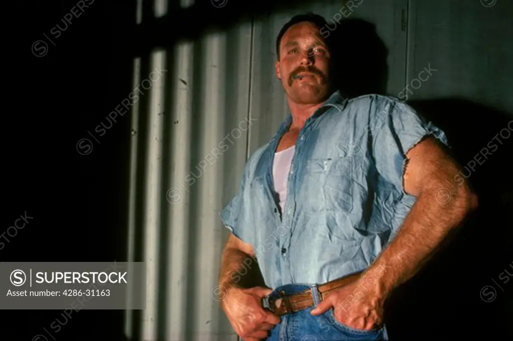 Portrait of a male convict criminal inmate in a prison jail cell
