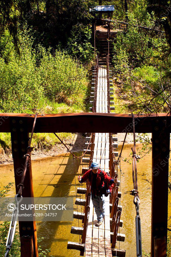 A father and son hiking across a suspension bridge that crosses Byers