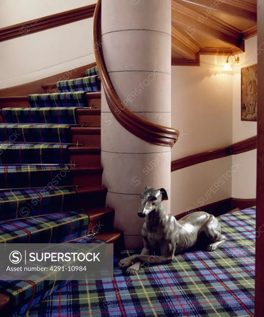 Blue and green tartan carpet on stairs and landing with statue of dog