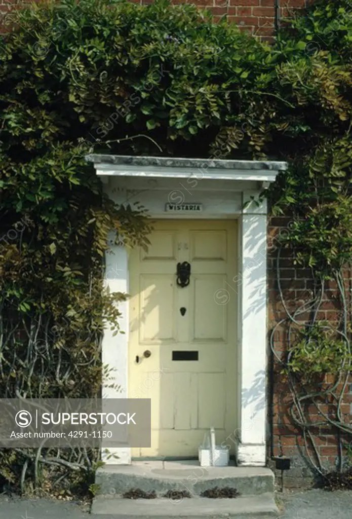Pastel yellow front door with white frame SuperStock